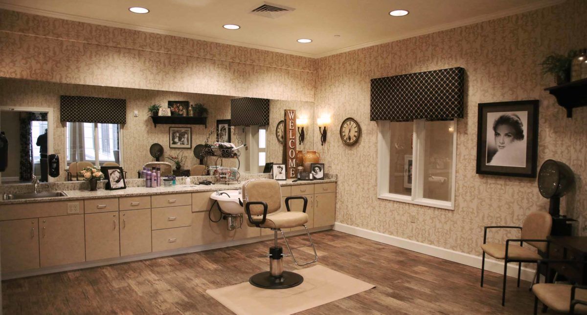 A cozy and well-decorated hair salon with a single styling chair, mirror, and counter.