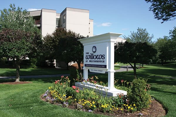 A residential apartment complex sign surrounded by well-maintained gardens.