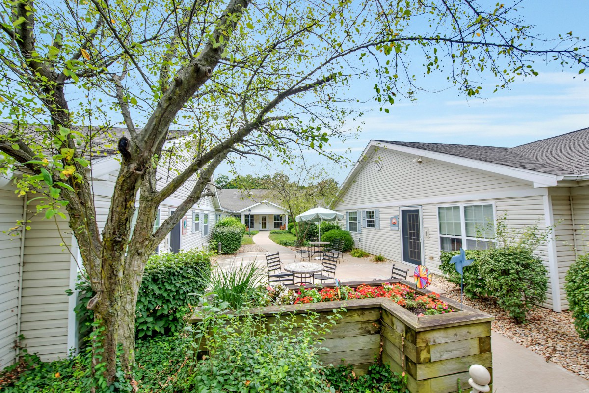 A serene outdoor patio area surrounded by lush greenery and residential buildings.