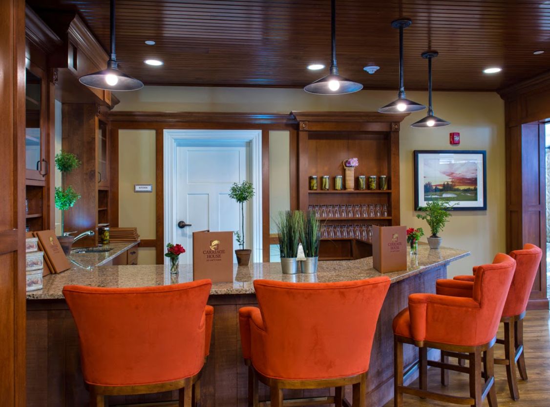 A cozy bar area with orange chairs and warm lighting.