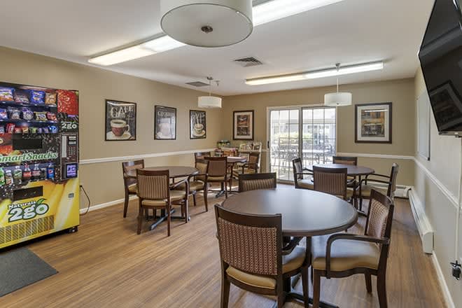 A cozy dining area featuring wooden tables and chairs, decorated with wall art and illuminated by ceiling lights.