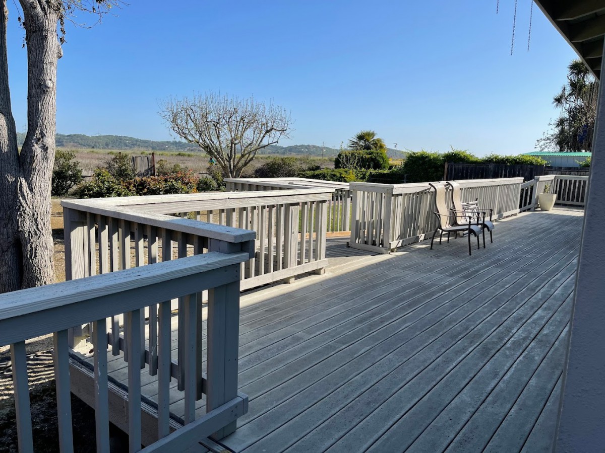 A spacious outdoor deck with furniture and a scenic view under a clear sky.