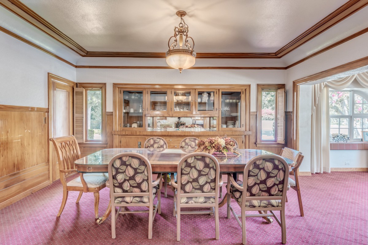 A classic dining room with a wooden table, floral upholstered chairs, and a chandelier.