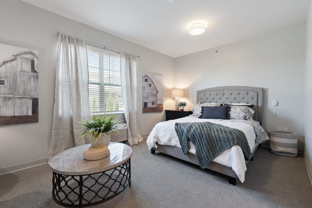 A cozy bedroom with modern decor, featuring a comfortable bed, a bedside lamp, and a window letting in natural light.