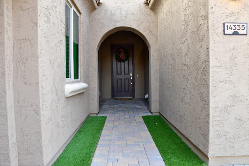 A welcoming entrance leading to a stylish front door, framed by an arch and lined with decorative grass.