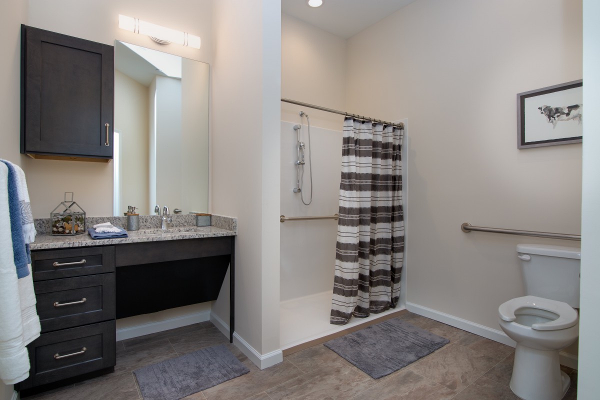 A modern and accessible bathroom featuring a sink, mirror, and striped shower curtain.