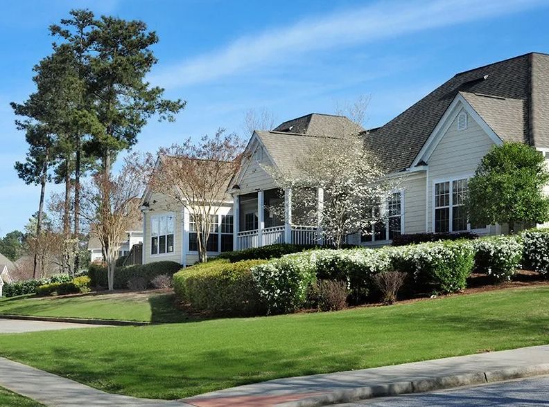 A suburban house with well-maintained landscaping and a clear blue sky.