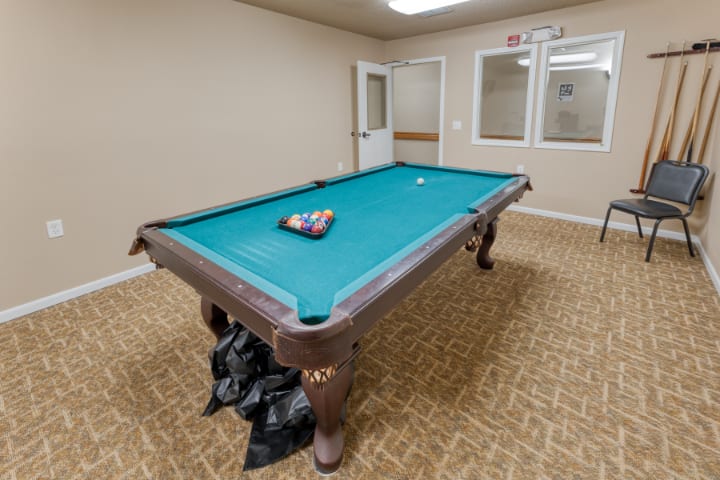 A well-lit game room featuring a pool table with balls set for play.