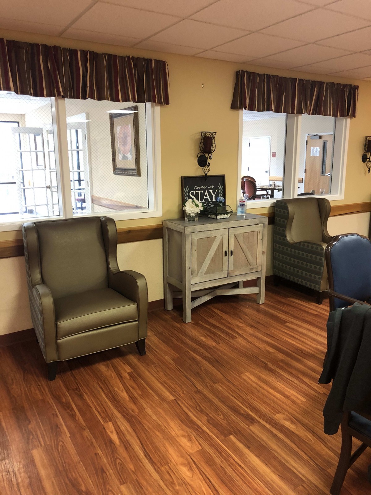 A cozy room with armchairs and a cabinet on a wooden floor.