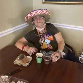 A person wearing a sombrero sits at a table with food and drinks, smiling.