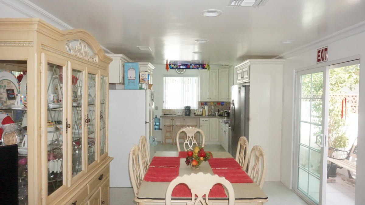 A well-lit kitchen and dining area featuring a table with red placemats, surrounded by chairs, and modern appliances.