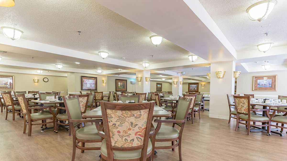 A spacious dining area with multiple tables and chairs, elegantly decorated with warm lighting.