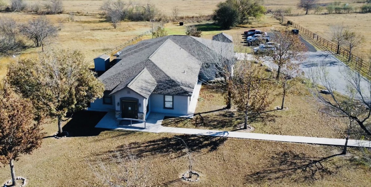 Aerial view of a suburban house surrounded by trees and a driveway.