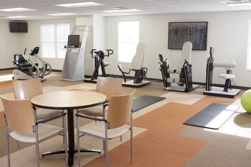 A modern gym with various exercise machines and a seating area.