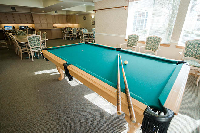 A billiards table with cues in a well-lit game room.