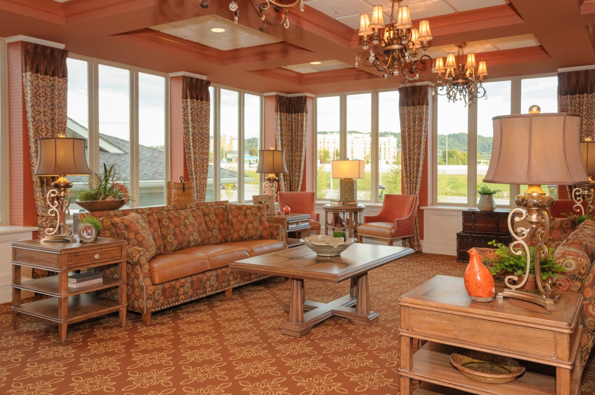 A cozy and stylish living room with large windows, elegant chandeliers, and comfortable furniture.