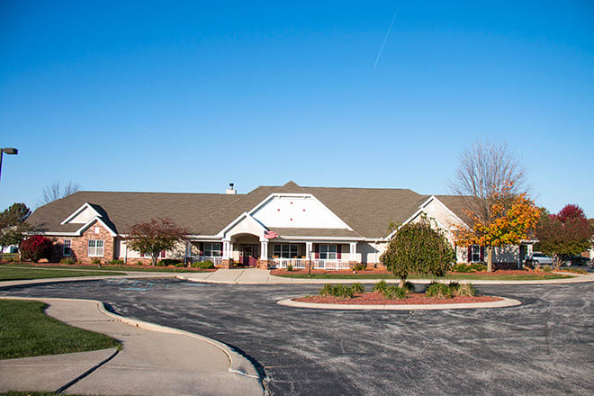 A suburban single-story residential building with neatly landscaped surroundings and a parking area.