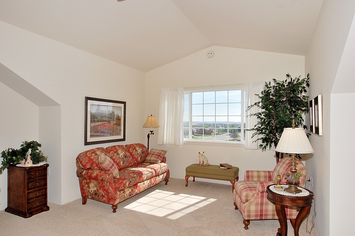 A cozy living room with floral-patterned furniture and a large window providing natural light.