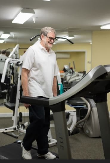 A senior man walking on a treadmill in the gym.