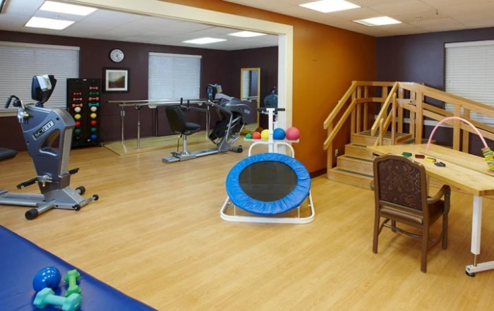 A rehabilitation room equipped with exercise machines, a trampoline, and stairs for physical therapy exercises.