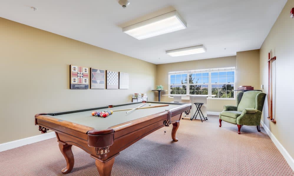 A well-lit game room featuring a pool table, chairs, and decorated walls.