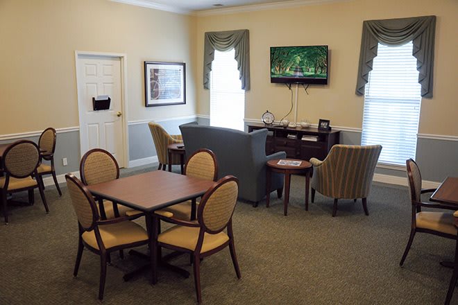A cozy living room featuring a television, seating area, and a table with chairs.