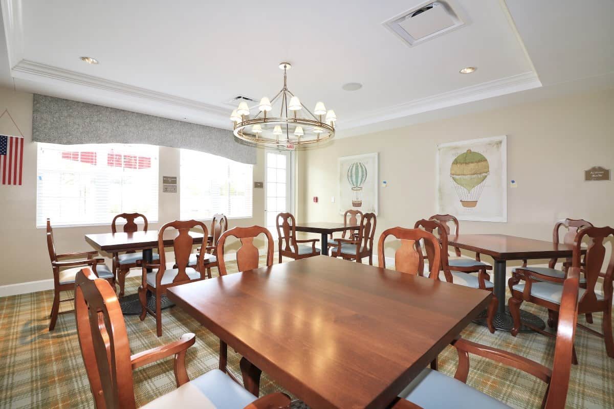A well-lit dining room with elegant wooden furniture and a modern chandelier.