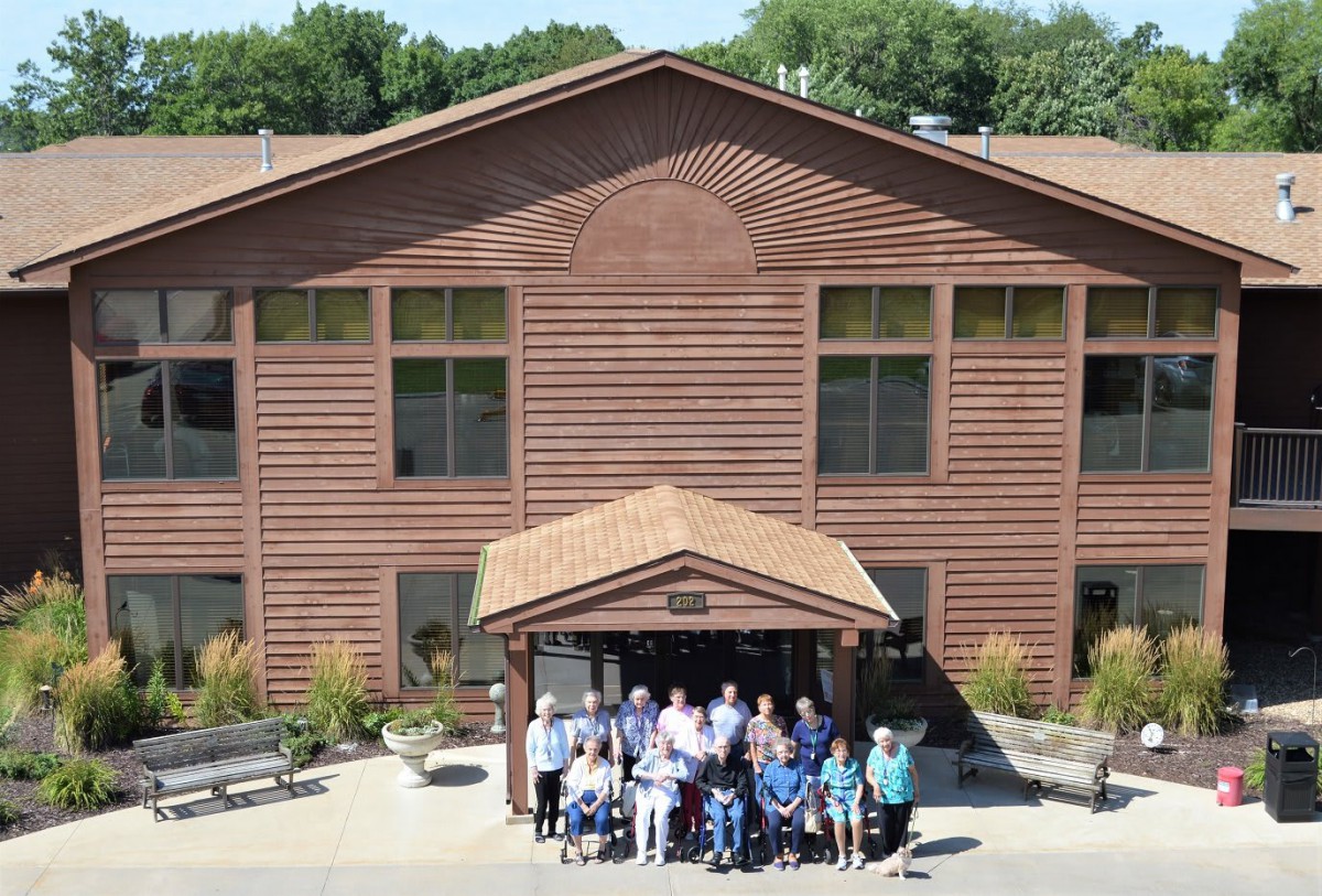 A group of people posing for a photo in front of a wooden building.