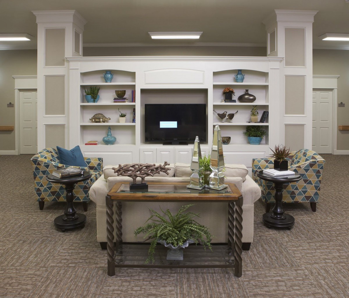 A cozy living room with elegant decor, featuring built-in shelves, a television, and comfortable seating.