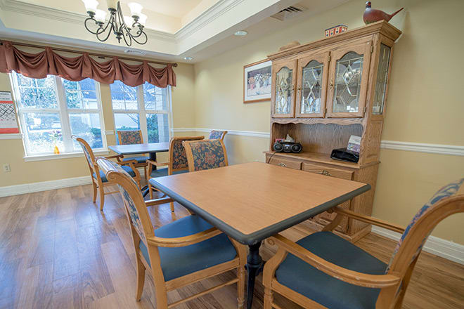A cozy dining room featuring a wooden table with chairs, a cabinet, and large windows allowing natural light.