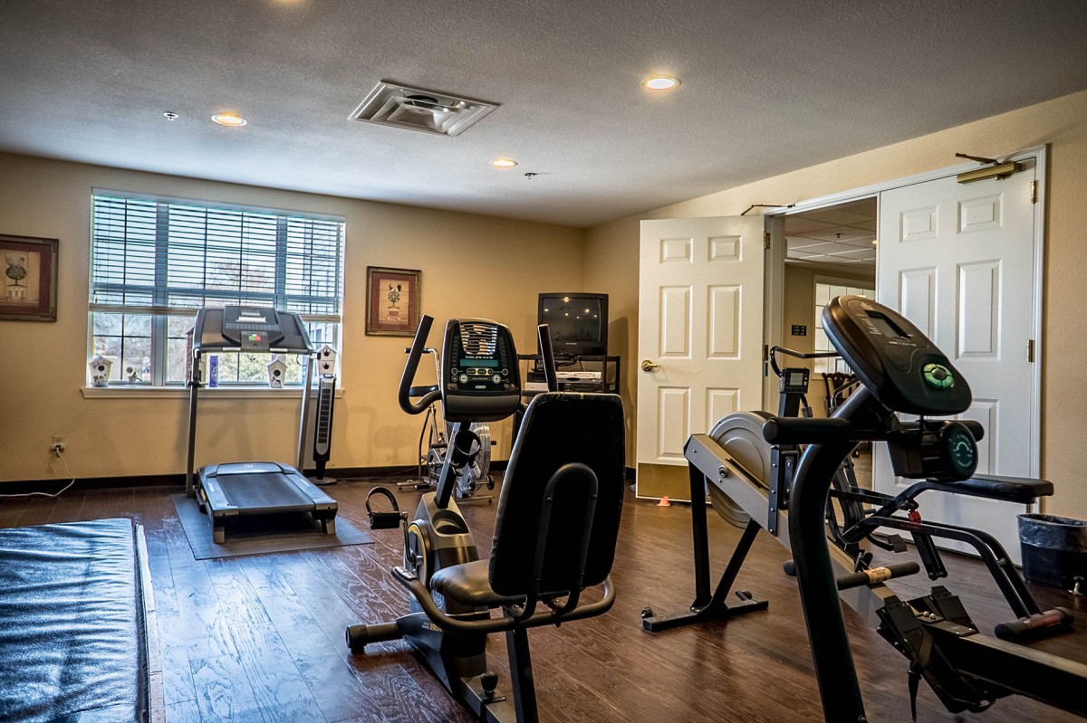 A home gym equipped with various exercise machines including a treadmill, stationary bike, and elliptical.