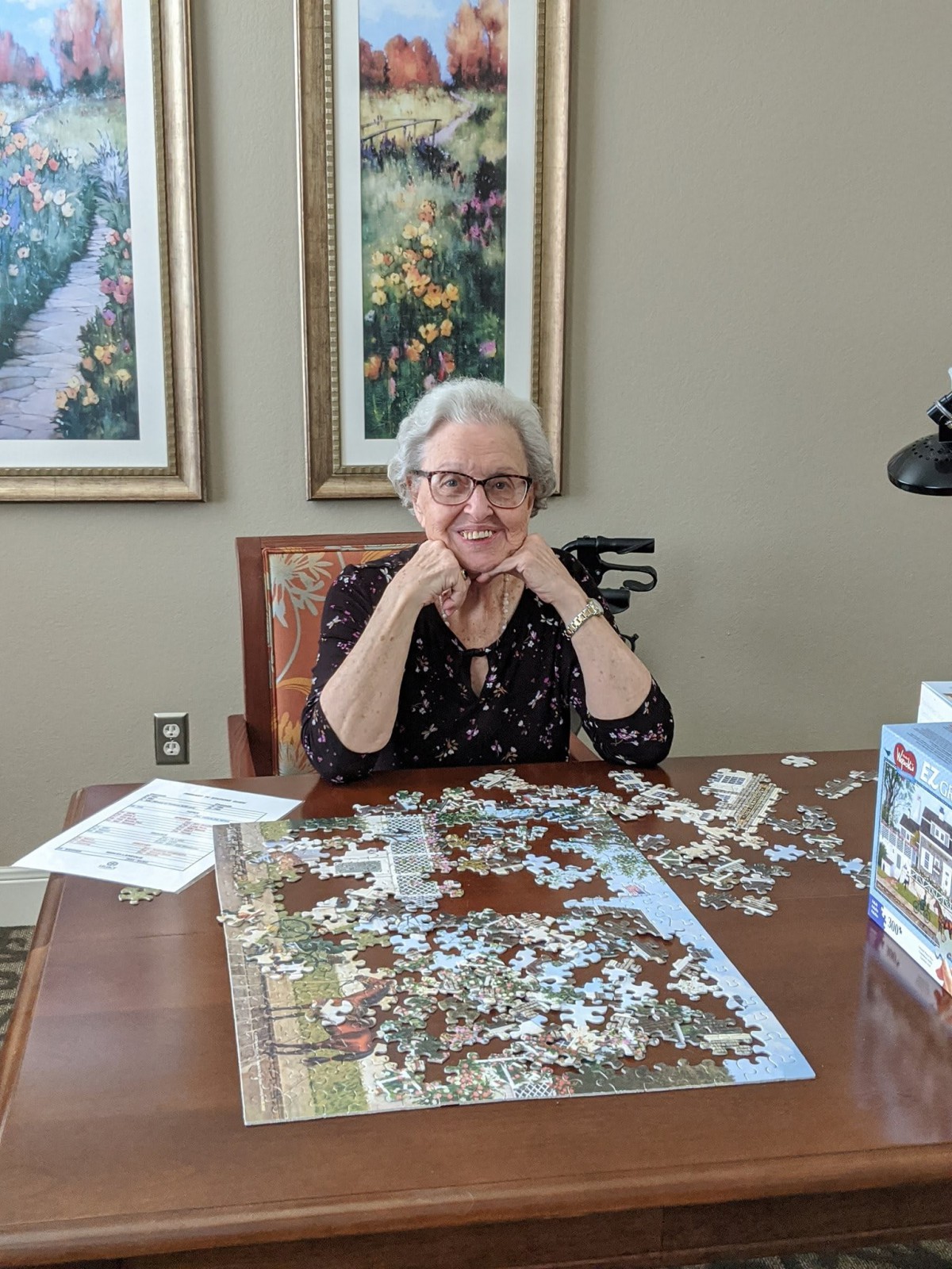 A woman enjoying assembling a puzzle at a table indoors.