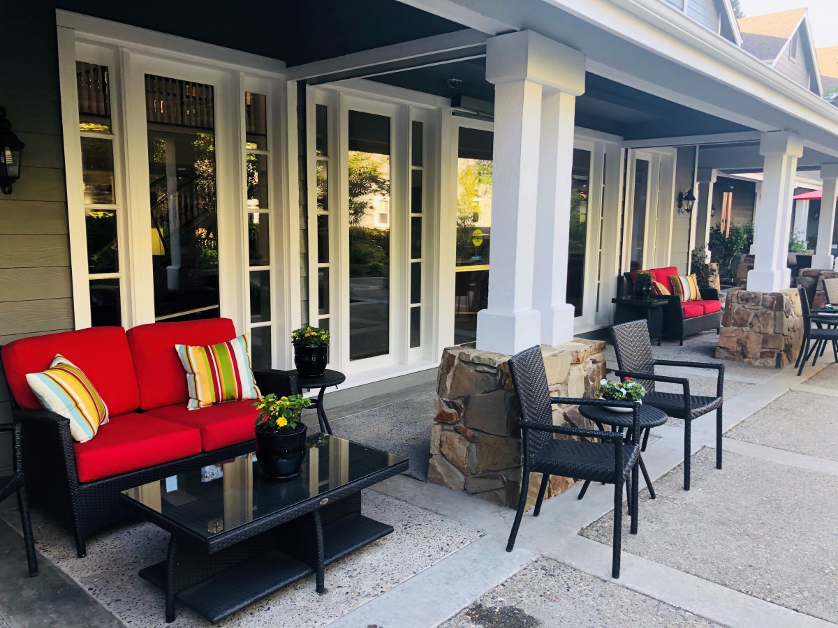 A cozy outdoor patio with red-cushioned furniture and tables set for relaxation.