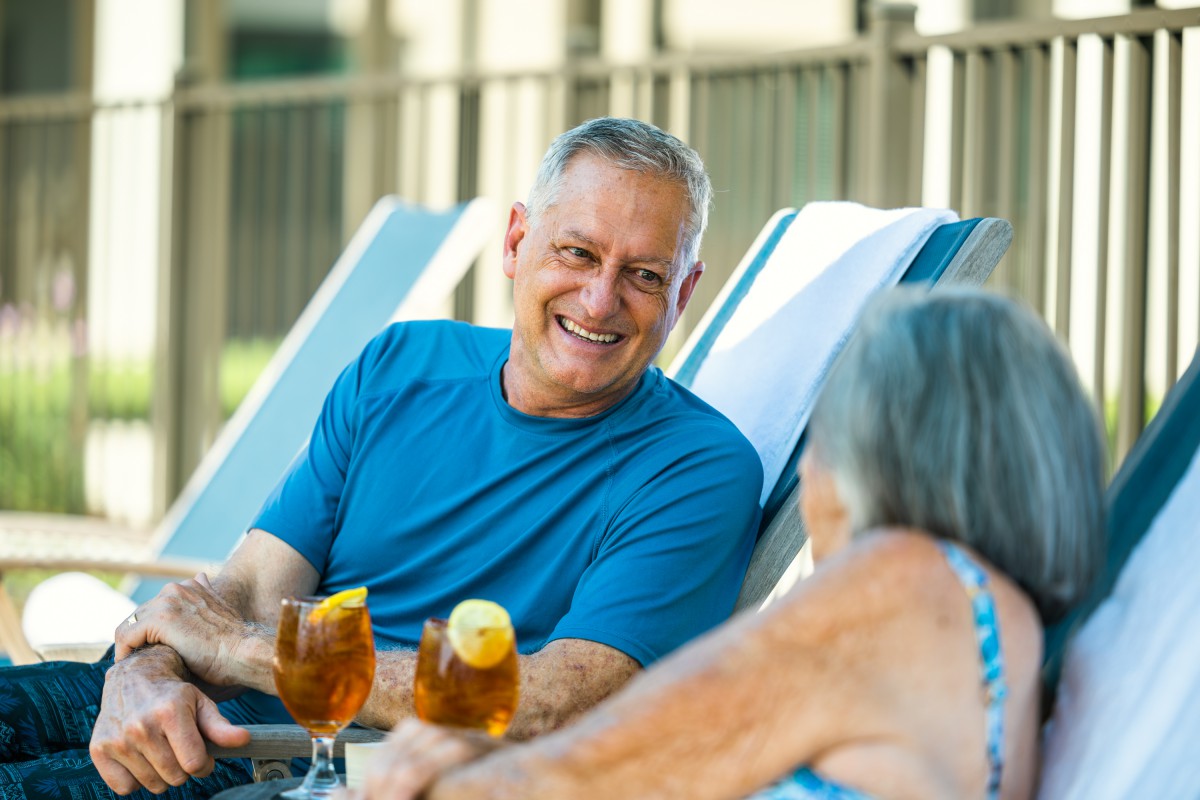 An elderly couple enjoying a relaxing conversation outdoors with drinks.