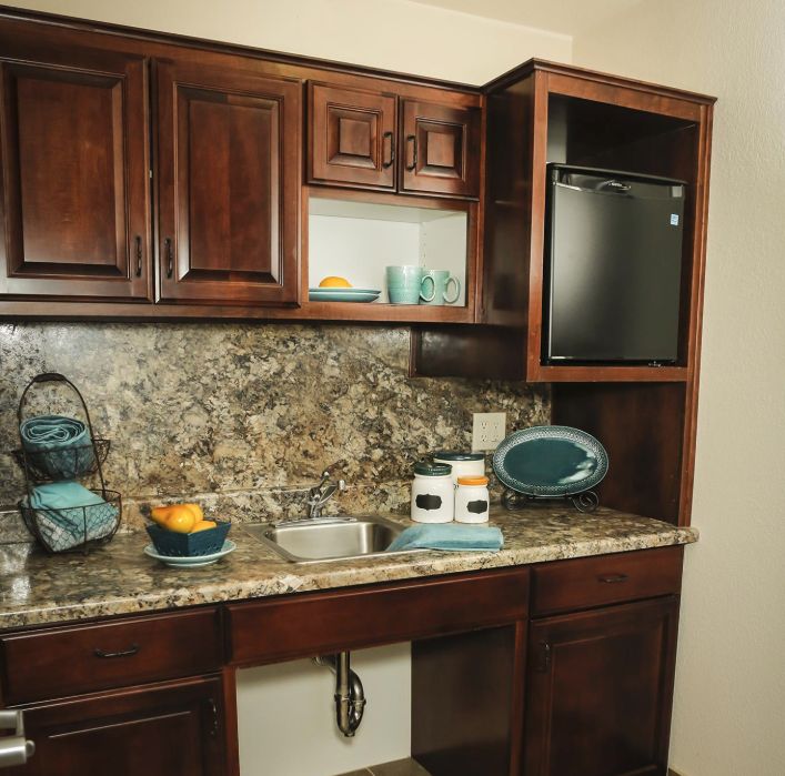 A kitchen with wooden cabinets, a granite countertop, and various appliances.