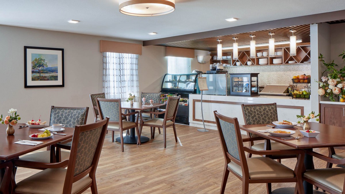 A cozy cafe interior with tables and chairs arranged near a service counter.