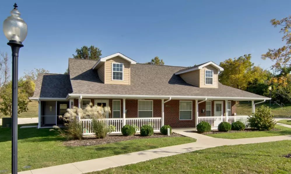 A charming suburban house with a front porch and well-maintained lawn.