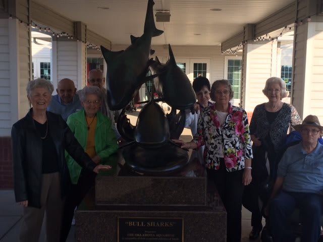 A group of people posing around a shark statue indoors.