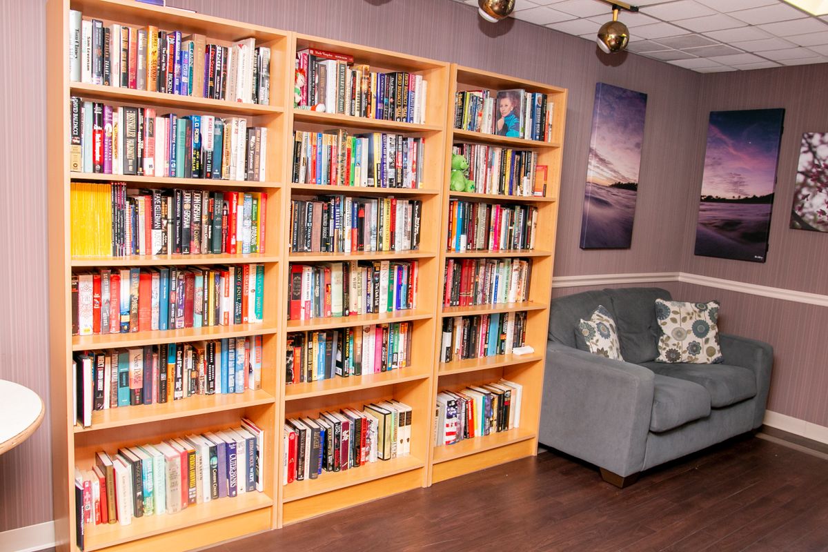 A cozy reading corner with a large bookshelf filled with various books and a comfortable sofa.