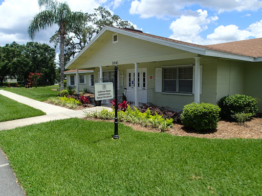 A charming residential building surrounded by lush greenery and colorful landscaping.