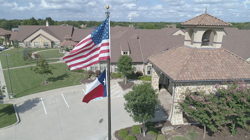The flags of the United States and Texas flying proudly in front of a residential building.