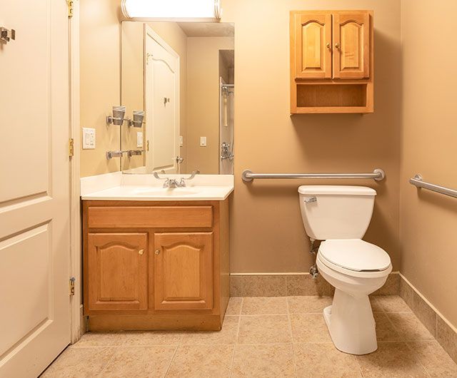A clean and simple bathroom with a toilet, sink, and wooden cabinets.