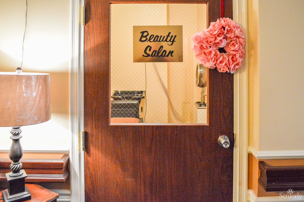 A beauty salon door with a sign and a flower wreath.