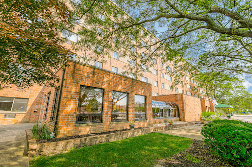 A view of a modern brick building surrounded by green grass and trees.