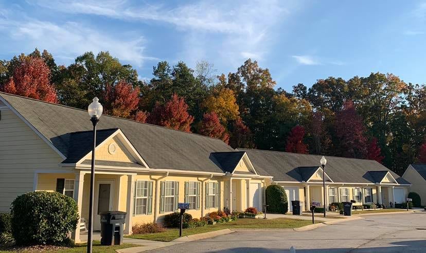 A row of suburban houses with colorful autumn trees in the background.