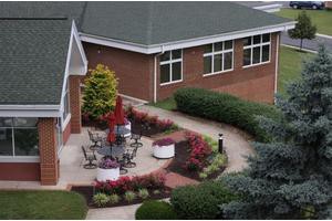 An aerial view of a landscaped garden with outdoor seating and a brick building in the background.