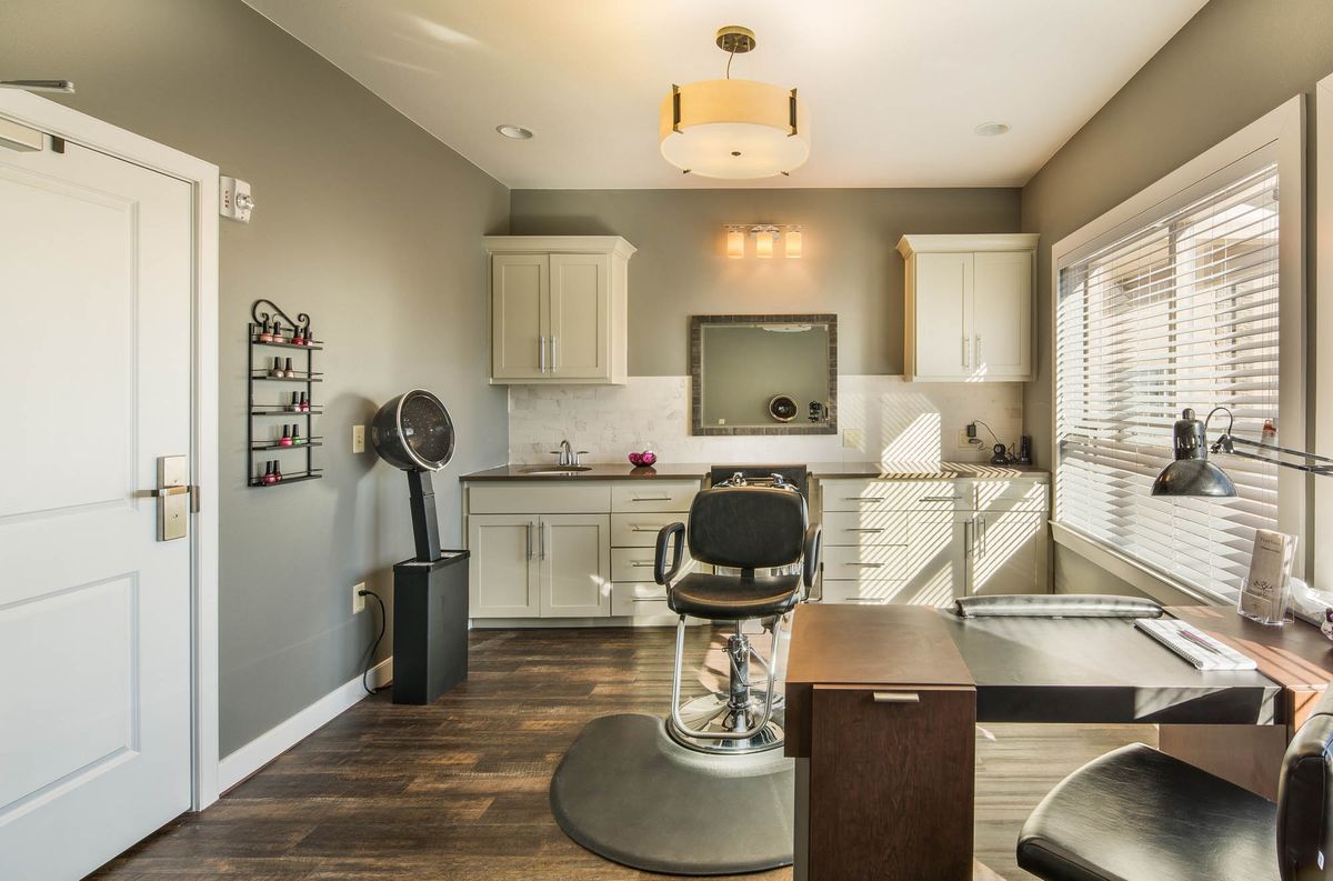 A modern hair salon interior with a styling chair and mirror, featuring sleek cabinets and a contemporary light fixture.