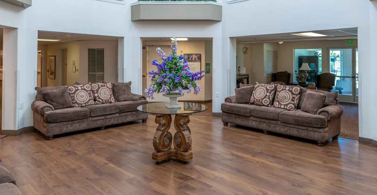 A cozy living room with sofas, a centerpiece table, and decorative flowers.
