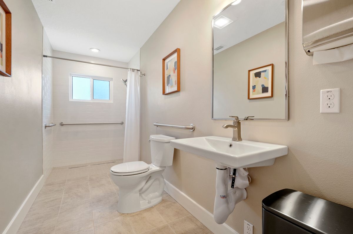A modern and minimalist bathroom with a large mirror, sink, and toilet.