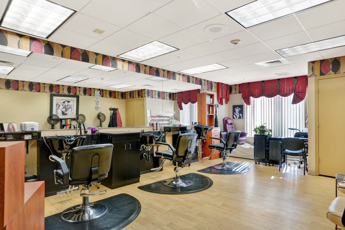 A spacious hair salon with multiple styling chairs, mirrors, and bright overhead lighting.